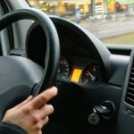 Photo of hands holding steering wheel of car to illustrate article on uber and lyft drivers as employees